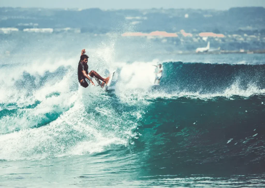 A surfer performs a dynamic maneuver on a wave, showcasing skill and energy in a vibrant ocean setting.